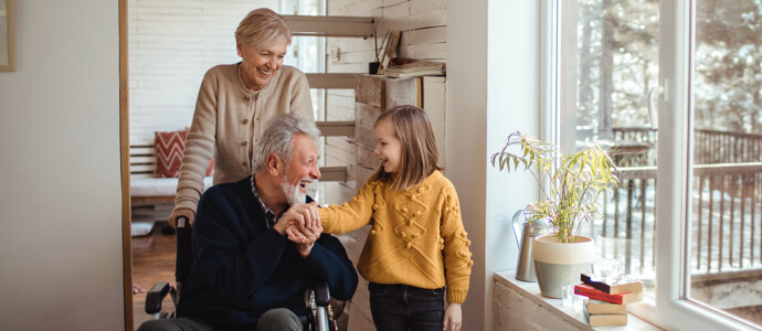 Senior couple with man in wheelchair meeting with their granddaughter